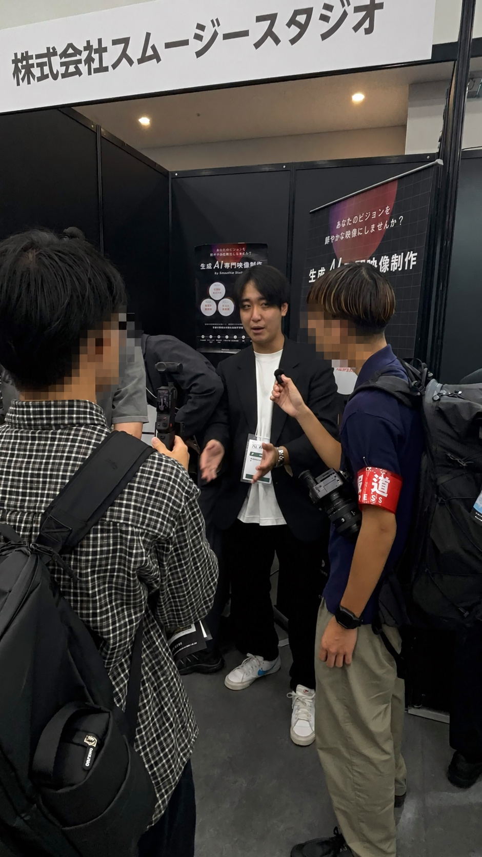 AI博覧会 Fukuoka 2026のブースで取材を受けるスムージースタジオ社員
